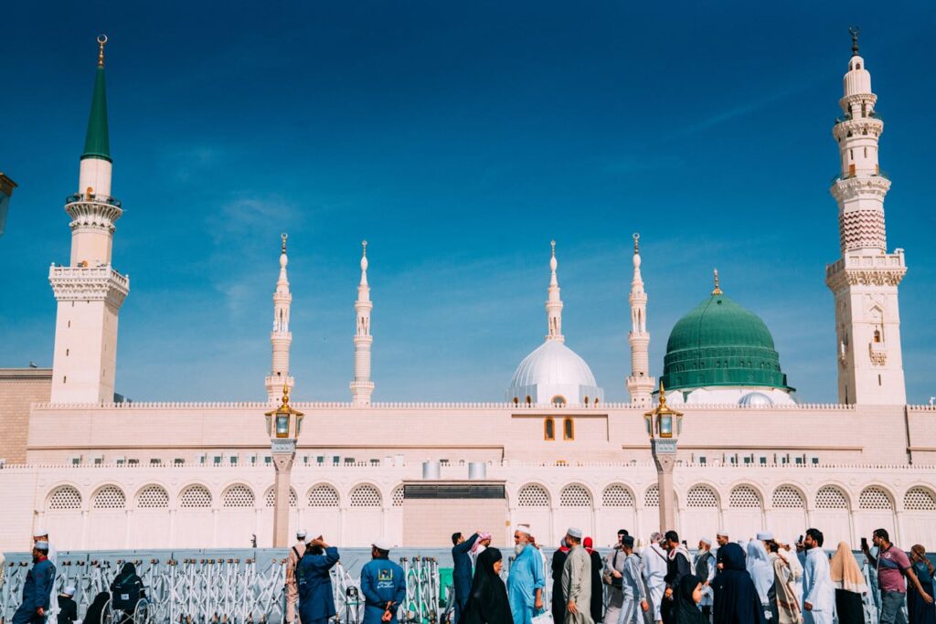 Crowds gather outside the majestic Prophet's Mosque on a sunny day in Medina, Saudi Arabia.